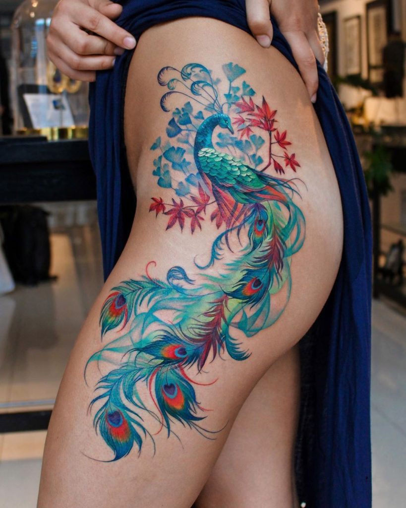 Tatuagem Pavão colorido na coxa. Tatuagem feminina. 